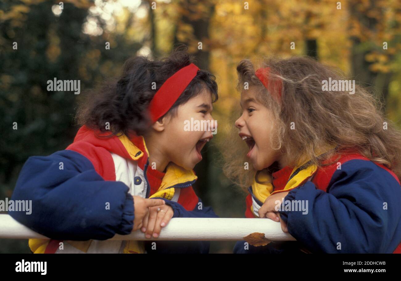 two little sisters in autumn wood face to face shouting Stock Photo