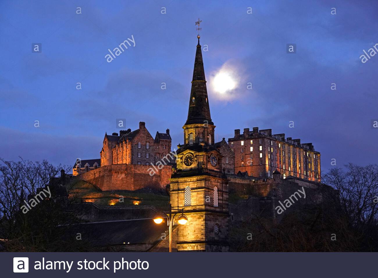 Edinburgh, Scotland, UK. 25th Nov 2020. Edinburgh city centre at dusk with an 81% waxing Gibbous Moon phase displaying over Edinburgh Castle and St Cuthbert's Church. Credit: Craig Brown/Alamy Live News Stock Photo