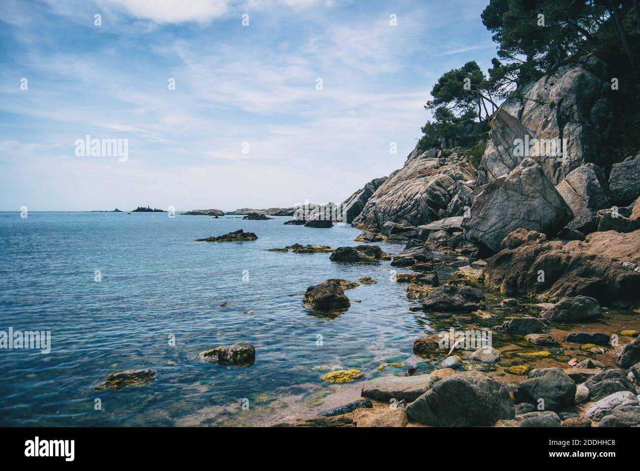 Landscape of a small pebble beach surrounded by rocks with vegetation in Costa Brava Stock Photo