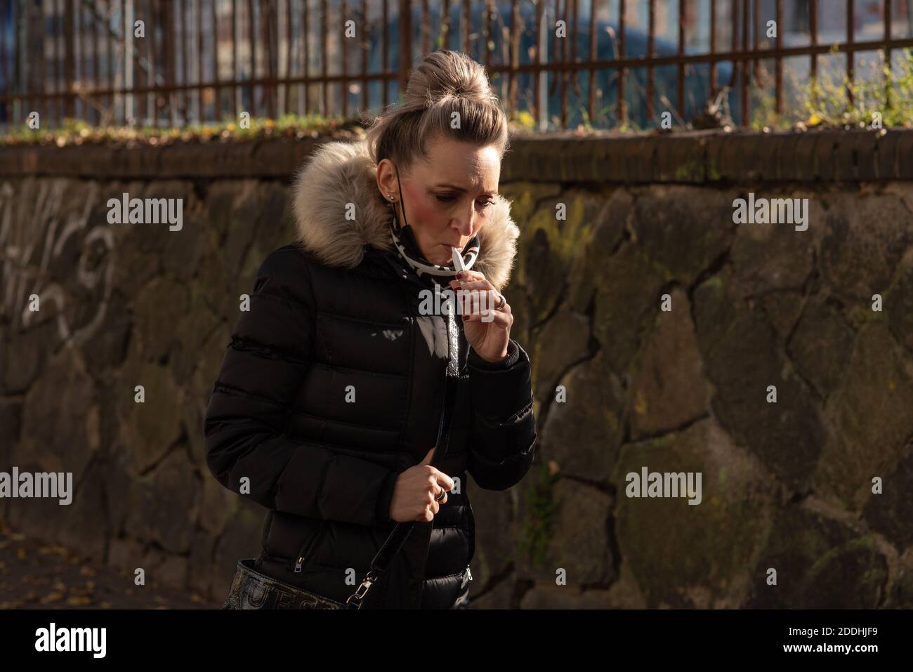 11-23-2020. Prague, Czech Republic. People walking and talking outside during coronavirus (COVID-19) at Hradcanska metro stop in Prague 6. Woman smoki Stock Photo