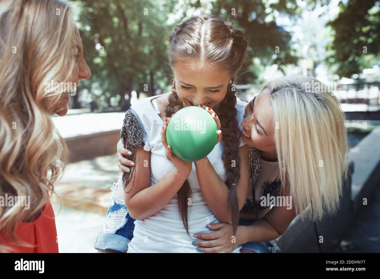Three girlfriends having fun and blowing balloons Stock Photo