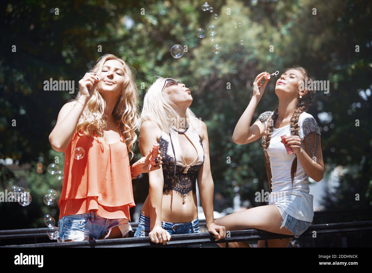 Three girlfriends blowing bubbles outdoors Stock Photo Alamy