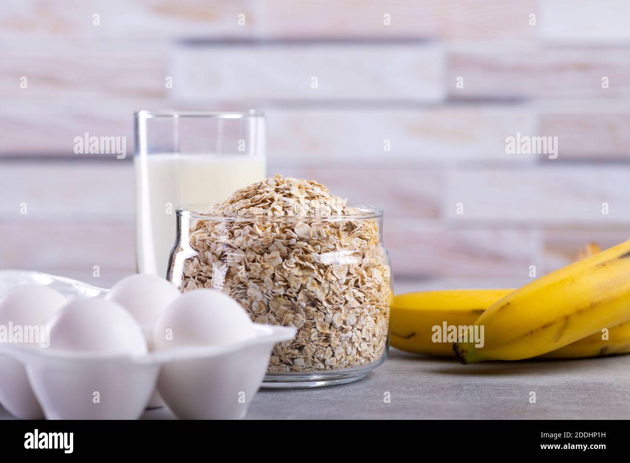 Oat pancakes with banana. Step by step cooking process. Ingredients top view. Bananas, milk, eggs, oats, salt. Wooden table background. Copy space Stock Photo