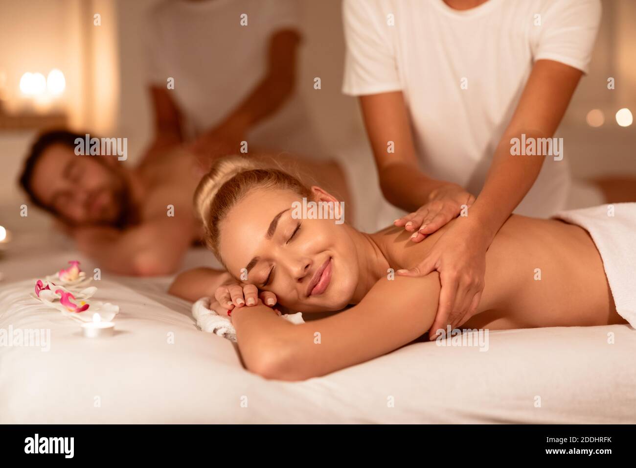 Happy Couple Relaxing Lying In Luxury Spa Receiving Back Massage Stock Photo