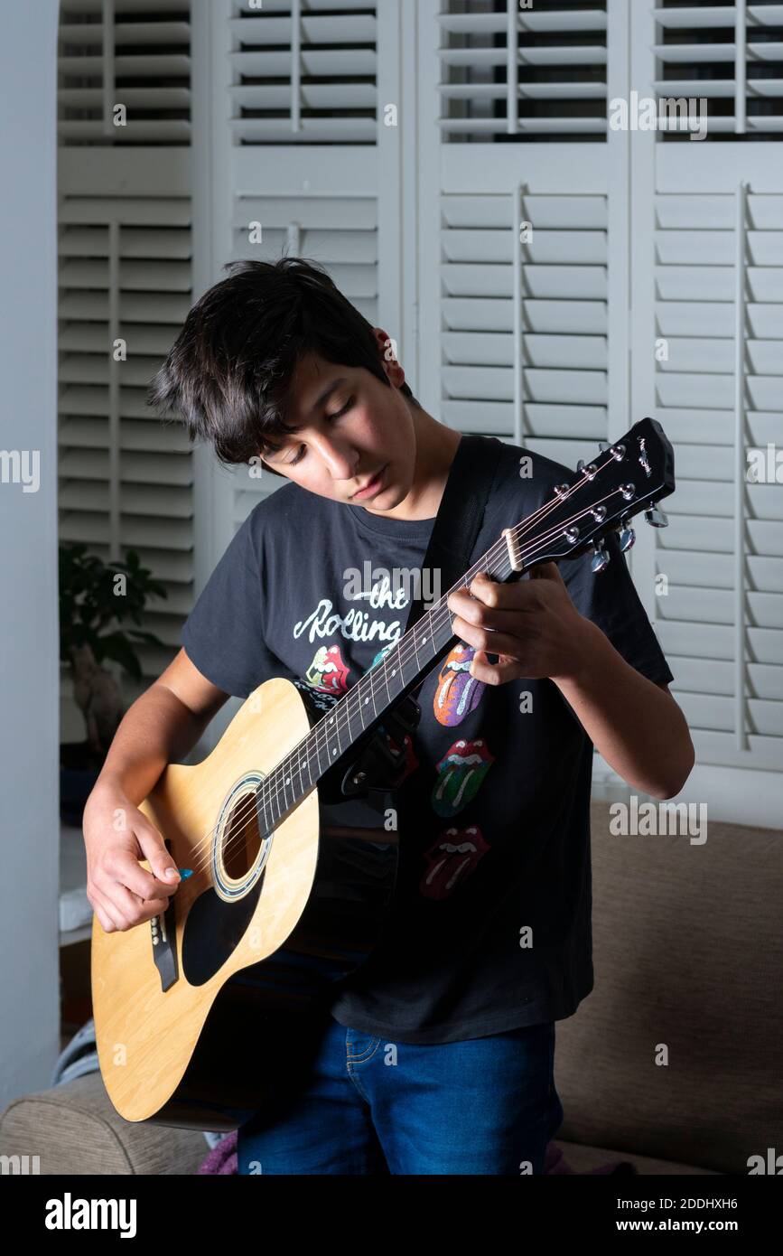 Teenage boy  learning acoustic guitar at home, UK Stock Photo