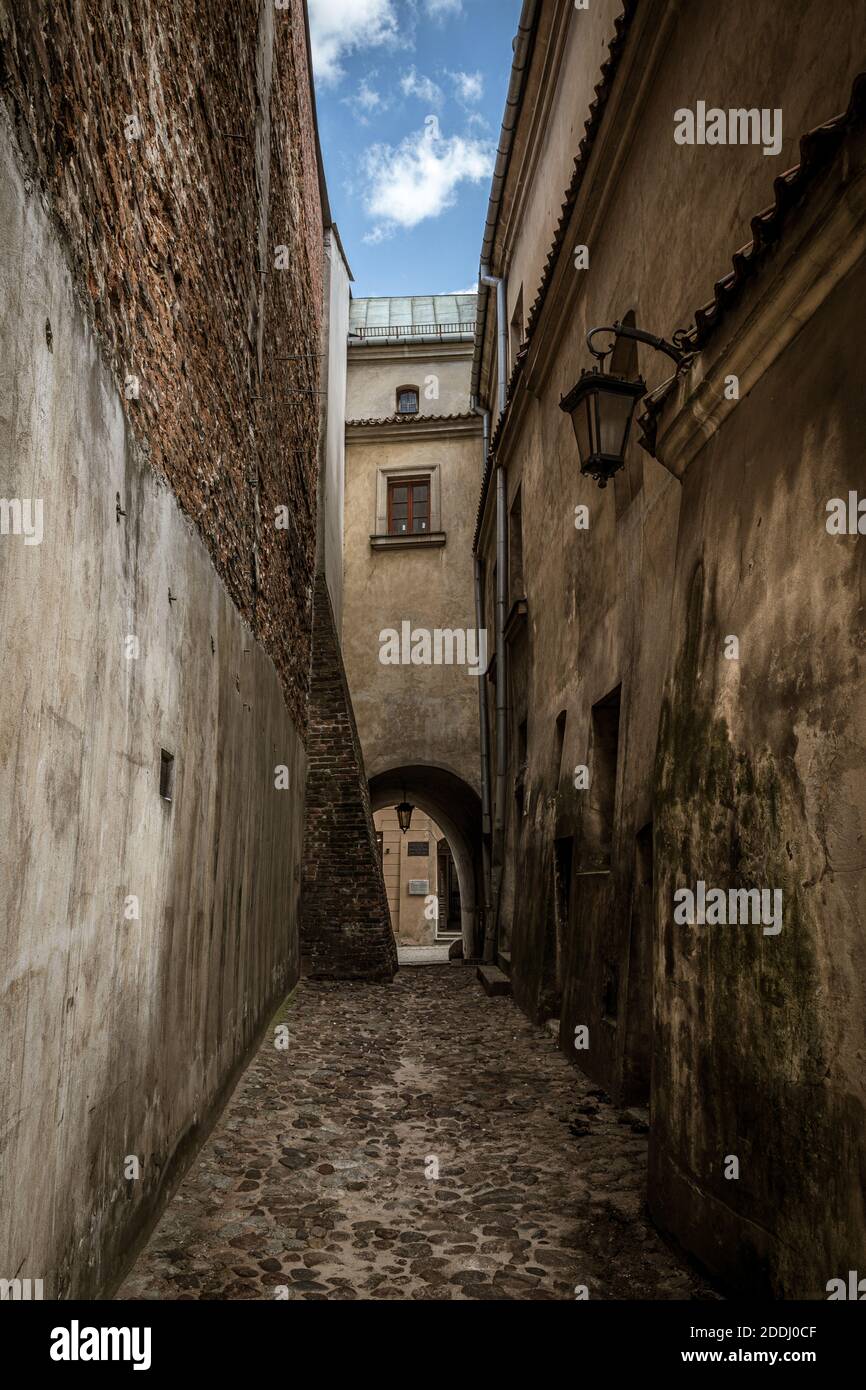 A vertical shot of a narrow alley of aged buildings under a blue sky at ...