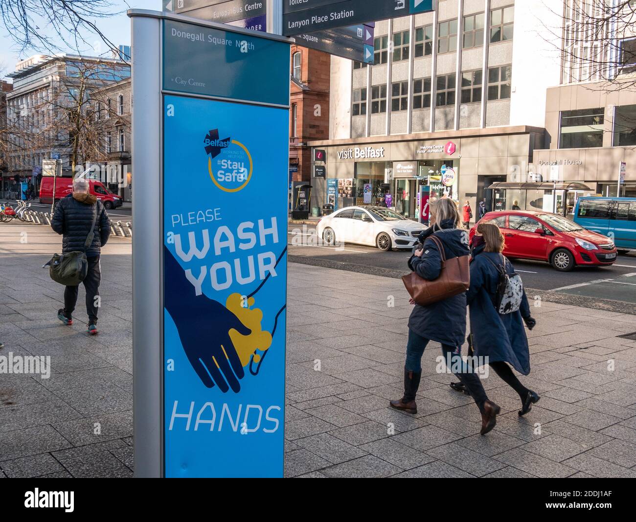 Belfast, Northern Ireland, UK, 25 November 2020: People walk past a sign in Donegall Square North reminding the public  to Wash Your Hands Stock Photo