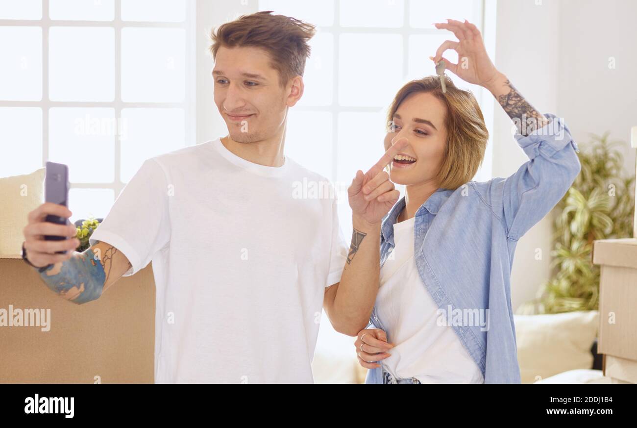 Happy smiling young couple showing a pair of keys of their new house ...