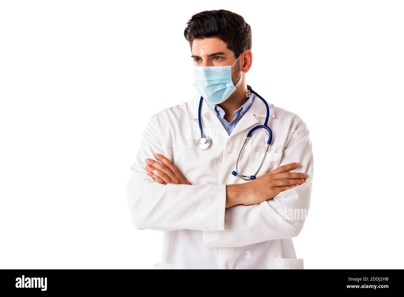 Portrait shot of male doctor wearing face mask while standing with arms crossed at isolated white background. Copy space. Stock Photo