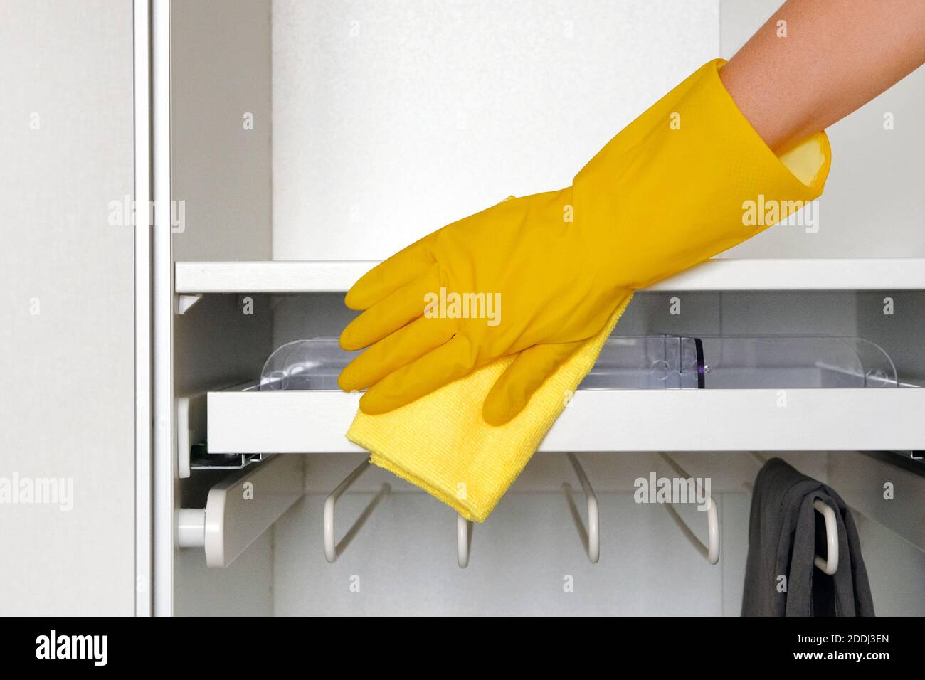 Hand in rubber protective glove with microfiber rag is cleaning cupboard in room. Household chores. Сleaning or regular clean up. Stock Photo