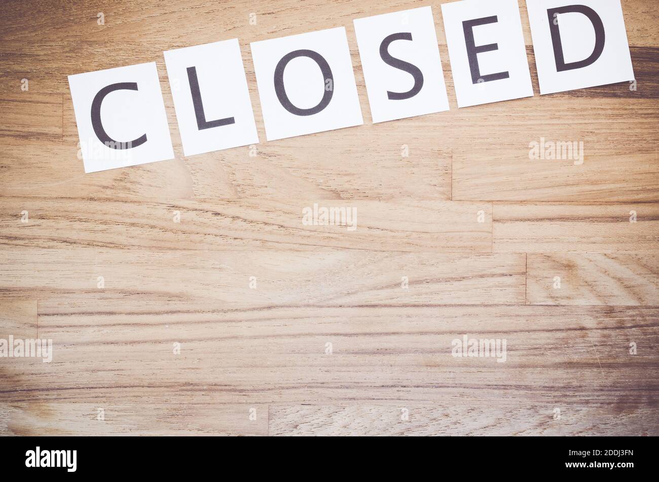 A top view of paper pieces with the word "closed" on wooden background