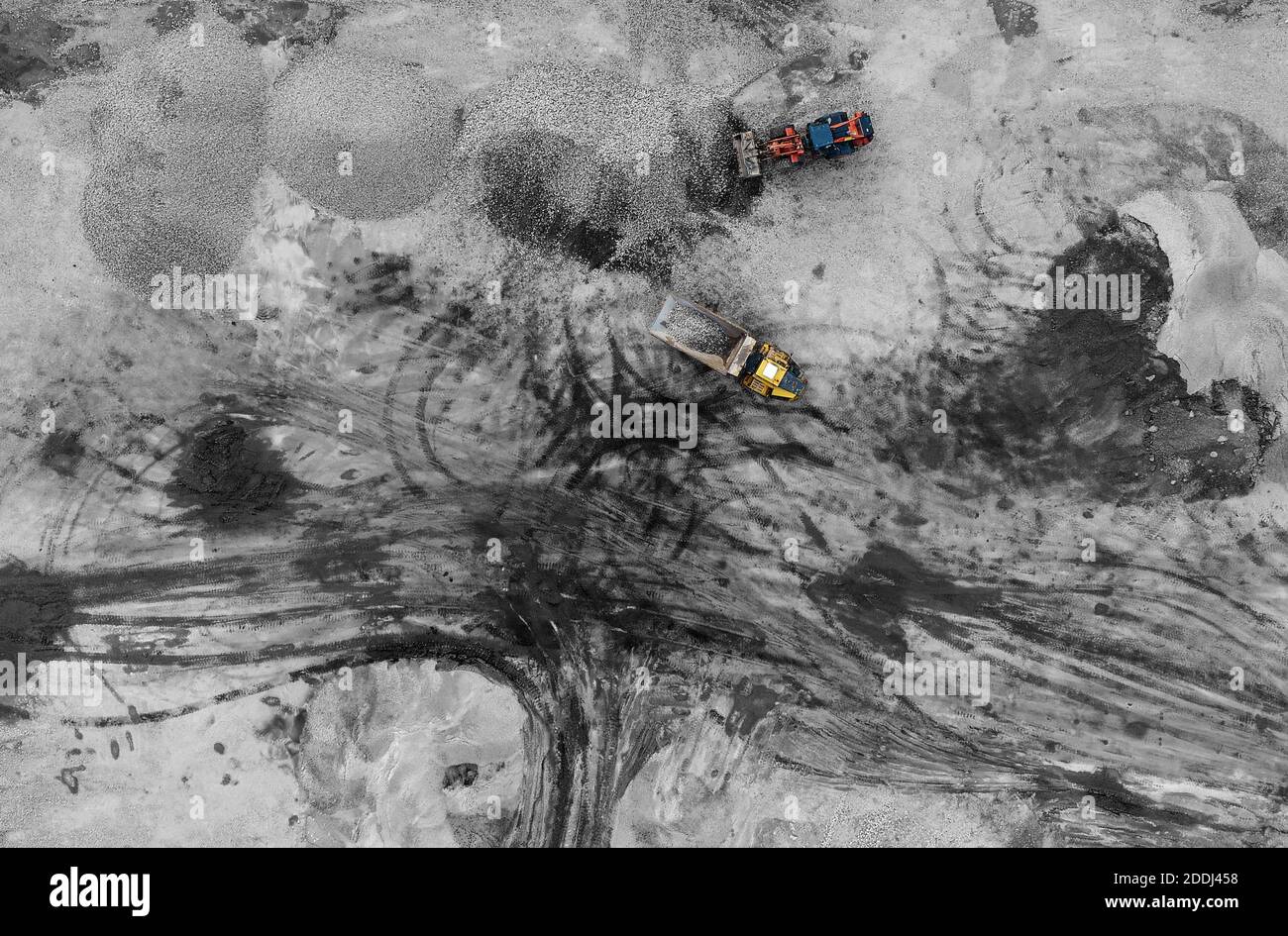 Heavy machines, including yellow trucks, in the working environment in a mine of aggregates, seen in an aerial photo taken from a drone Stock Photo