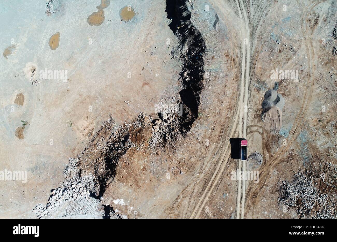 Heavy machines, including yellow trucks, in the working environment in a mine of aggregates, seen in an aerial photo taken from a drone Stock Photo