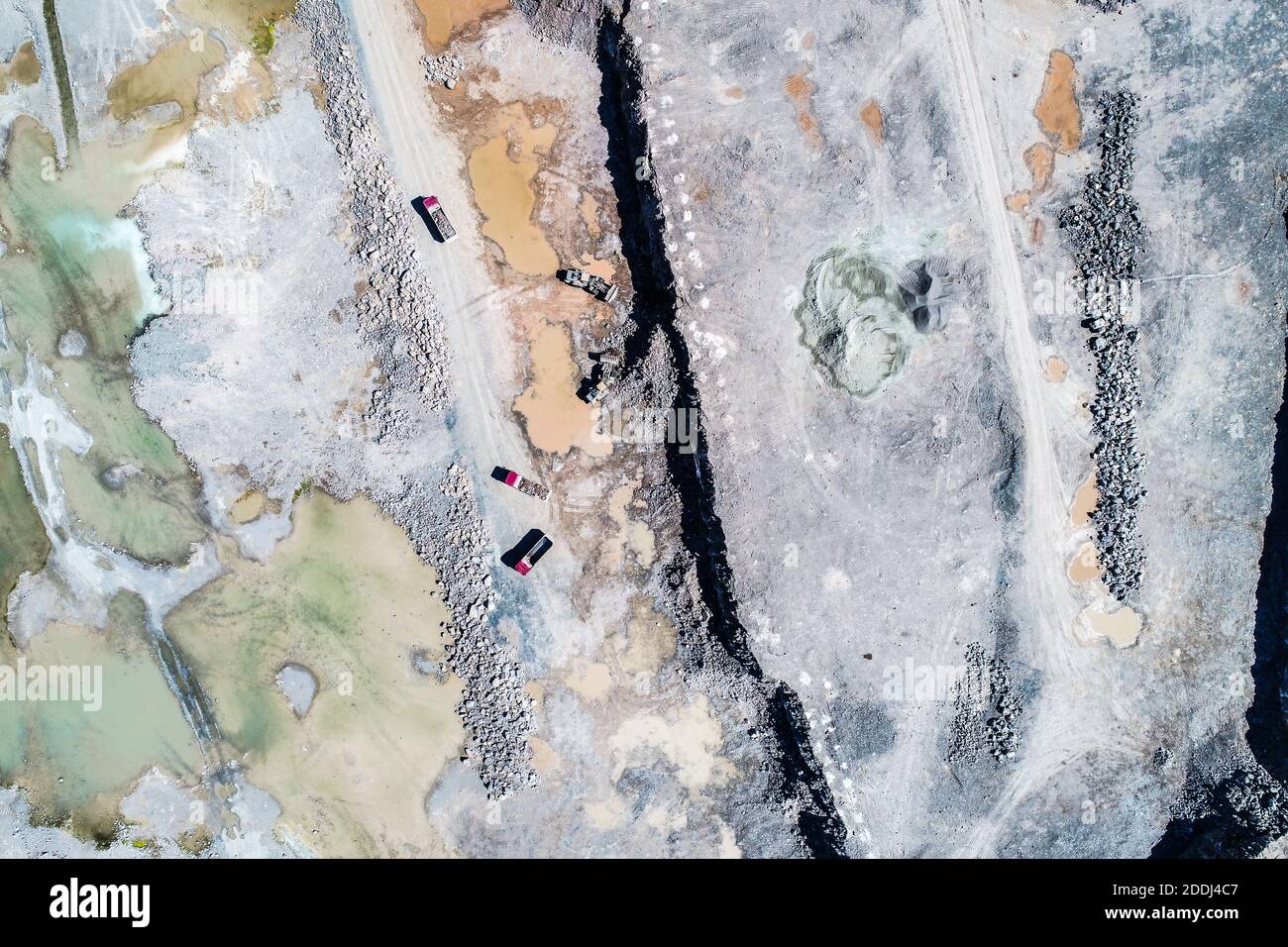 Heavy machines, including yellow trucks, in the working environment in a mine of aggregates, seen in an aerial photo taken from a drone Stock Photo