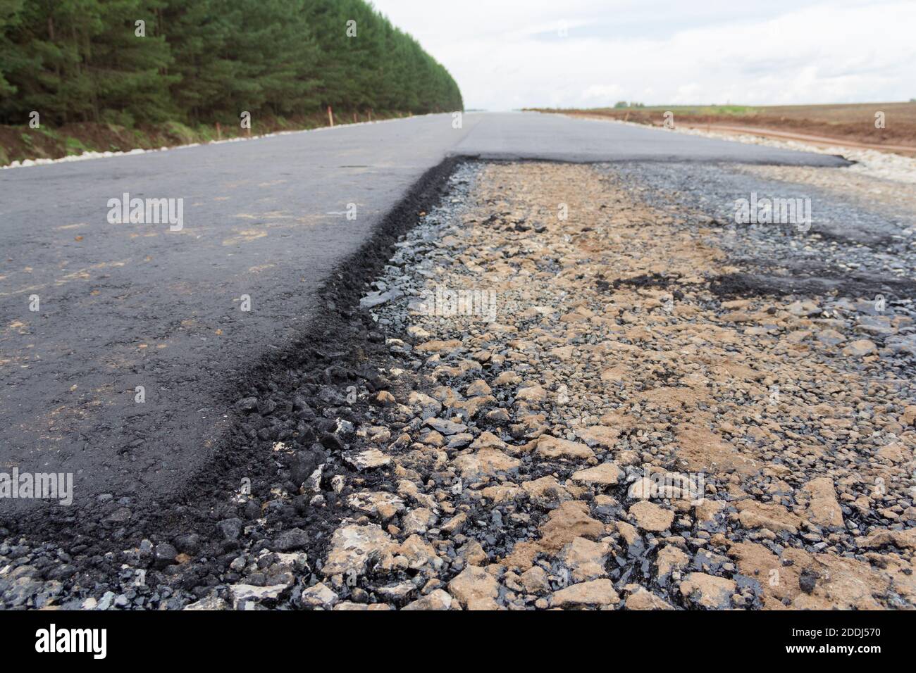 Stones on the edge of the asphalt road The border of the asphalt road and the shoulder. Stock Photo