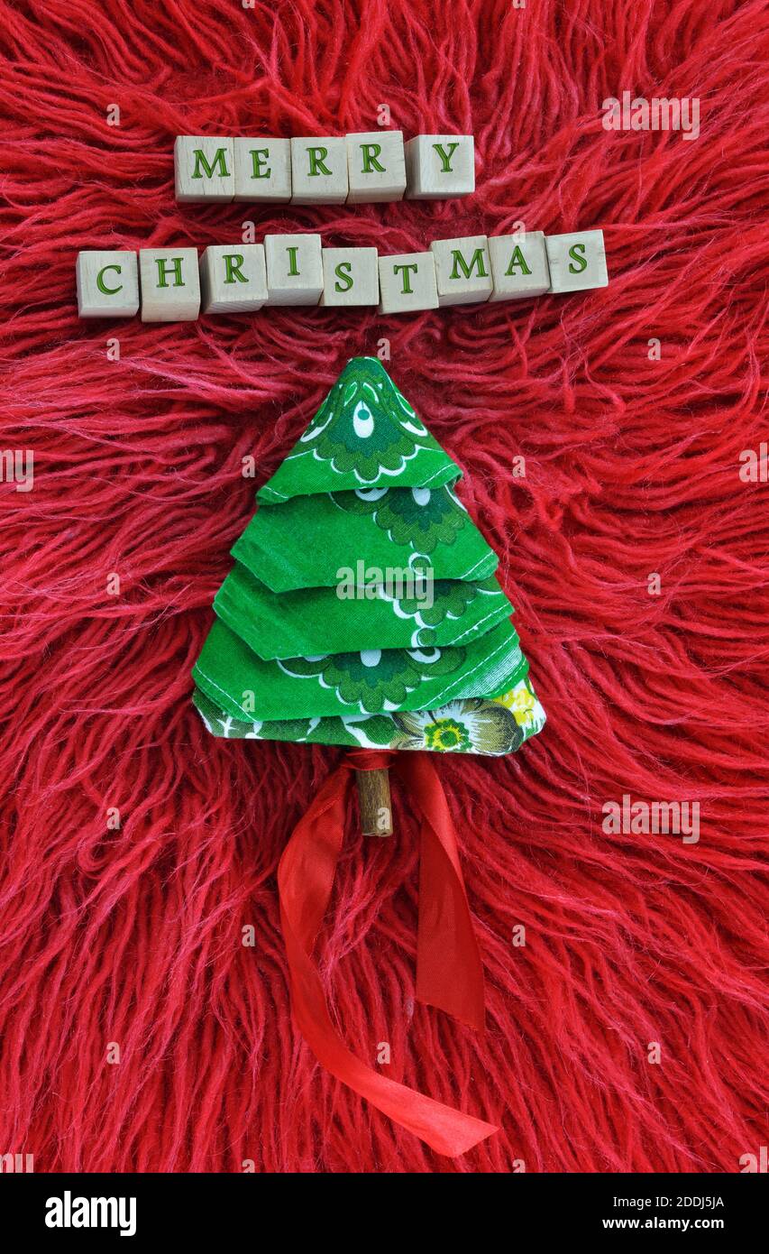 Christmas greeting text in wooden letters and towel in christmas tree ...