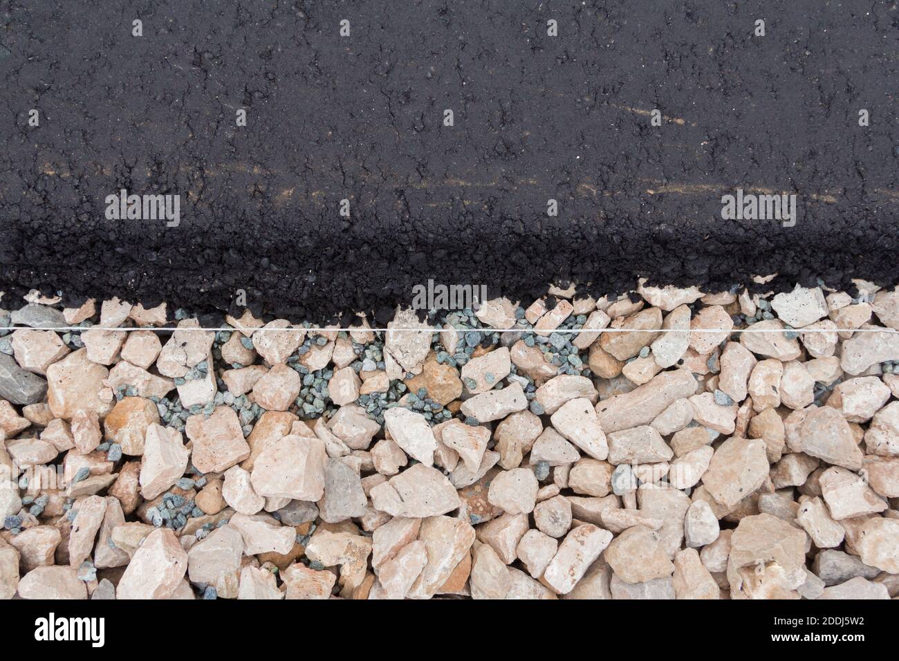 Stones on the edge of the asphalt road The border of the asphalt road and the shoulder. Stock Photo