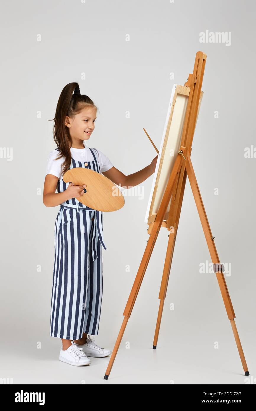 cute little girl holding a wooden art palette and brush on studio ...