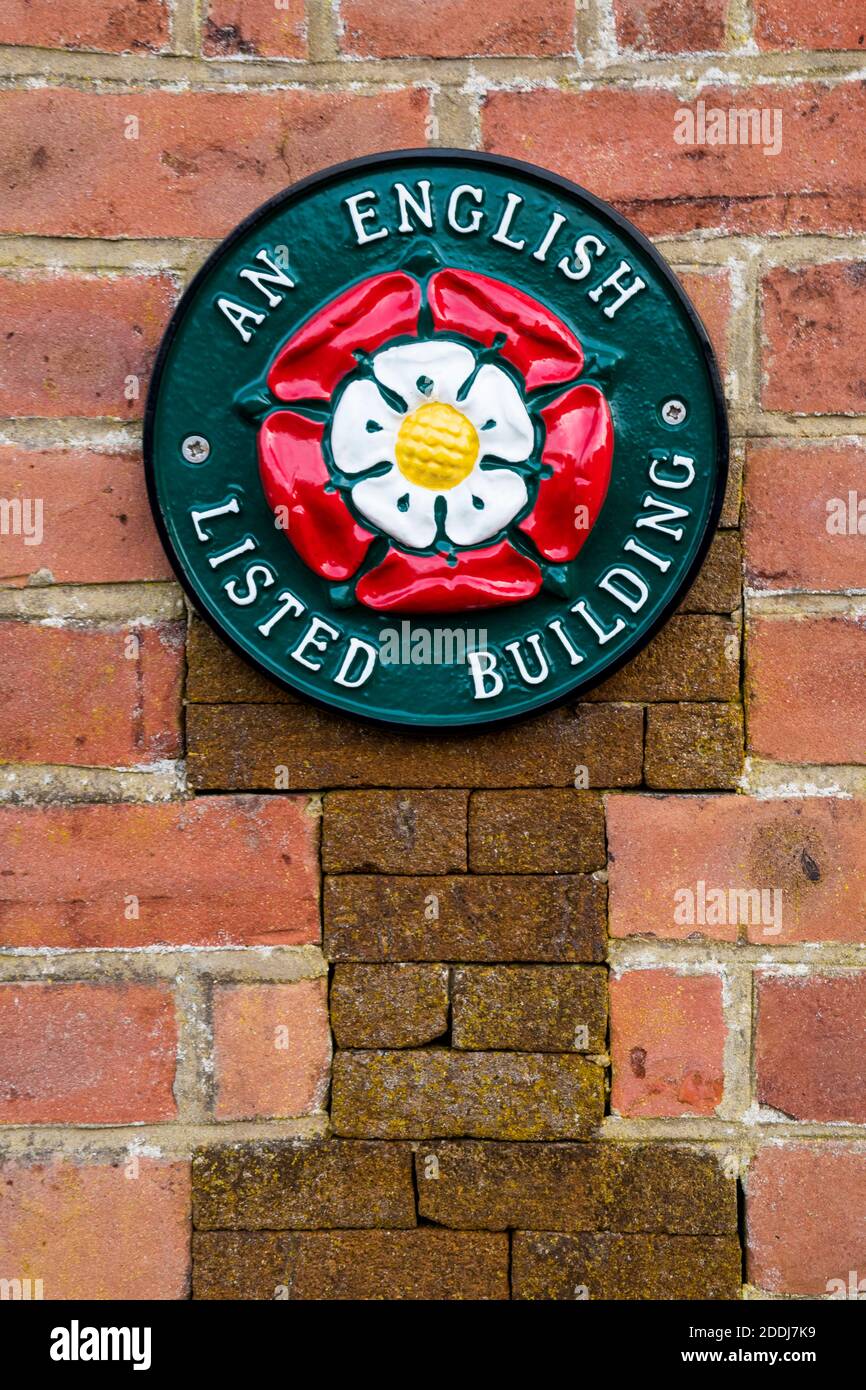 An English Listed Building sign on an historic building shows that it is included in the statutory list maintained by Historic England. Stock Photo