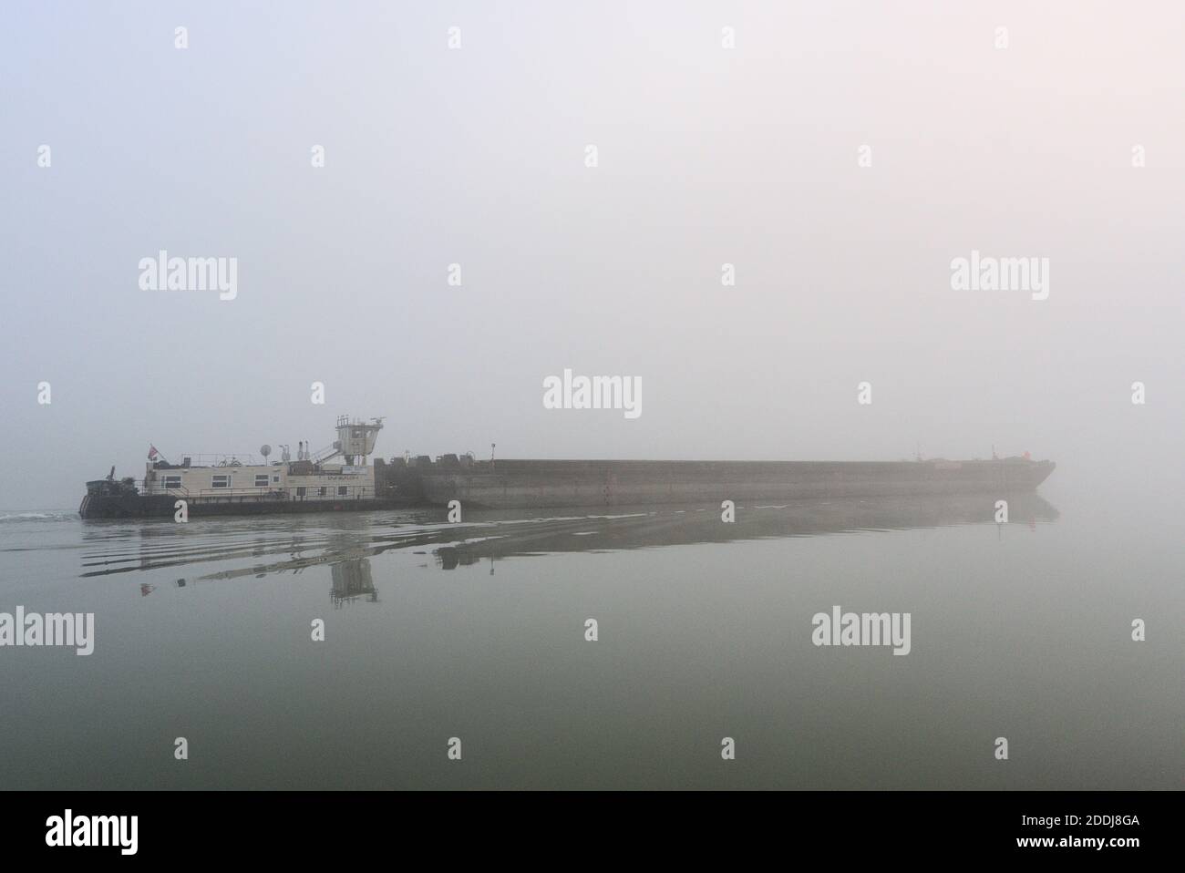 Schiff das im Nebel verschwindet mit orang gekleidetem Mann Stock Photo