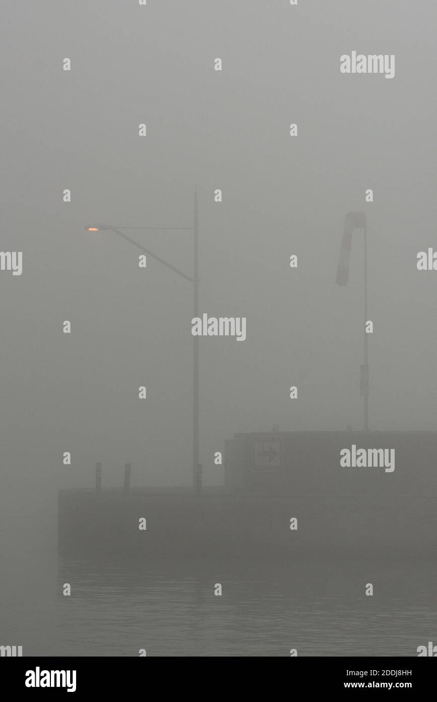 Lampe und Windhose im Nebel auf einer Mauer Stock Photo