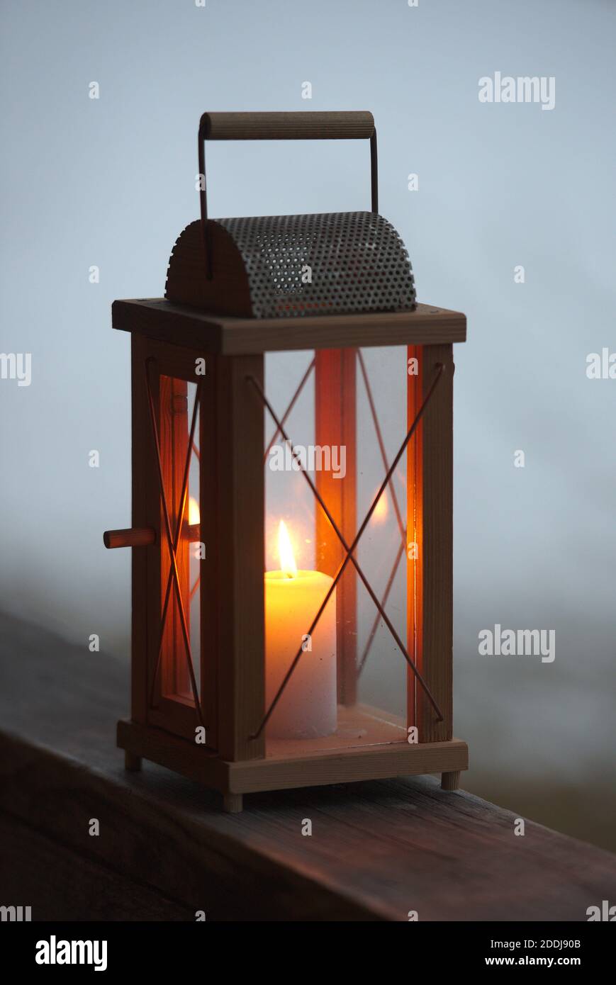 hölzerne Laterne mit leuchtendem Kerzenschein auf einem Balkon im Nebel Stock Photo