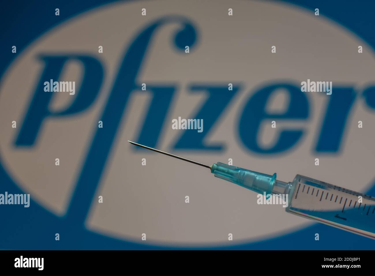Pfizer covid-19 vaccine in a syringe  in front of the company logo, Denmark, November 24, 2020 Stock Photo