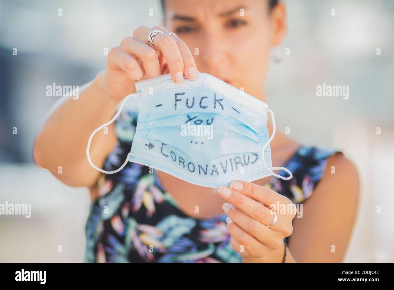 A woman holds a surgical mask with a phrase against coronavirus Stock Photo