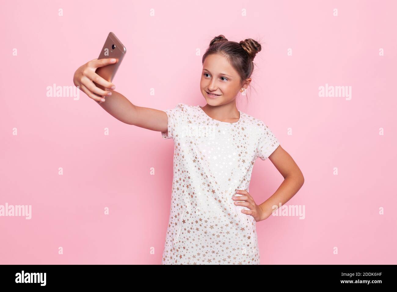 Cute girl in a pink dress, a teenager makes selfie on a mobile phone on a  pink background Stock Photo - Alamy