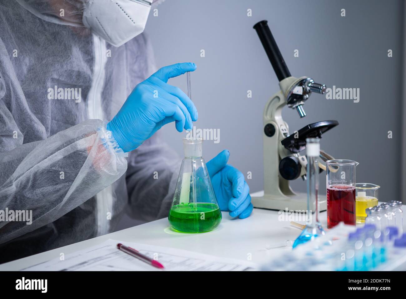 Technician in protective clothing hand stirring and shaking green