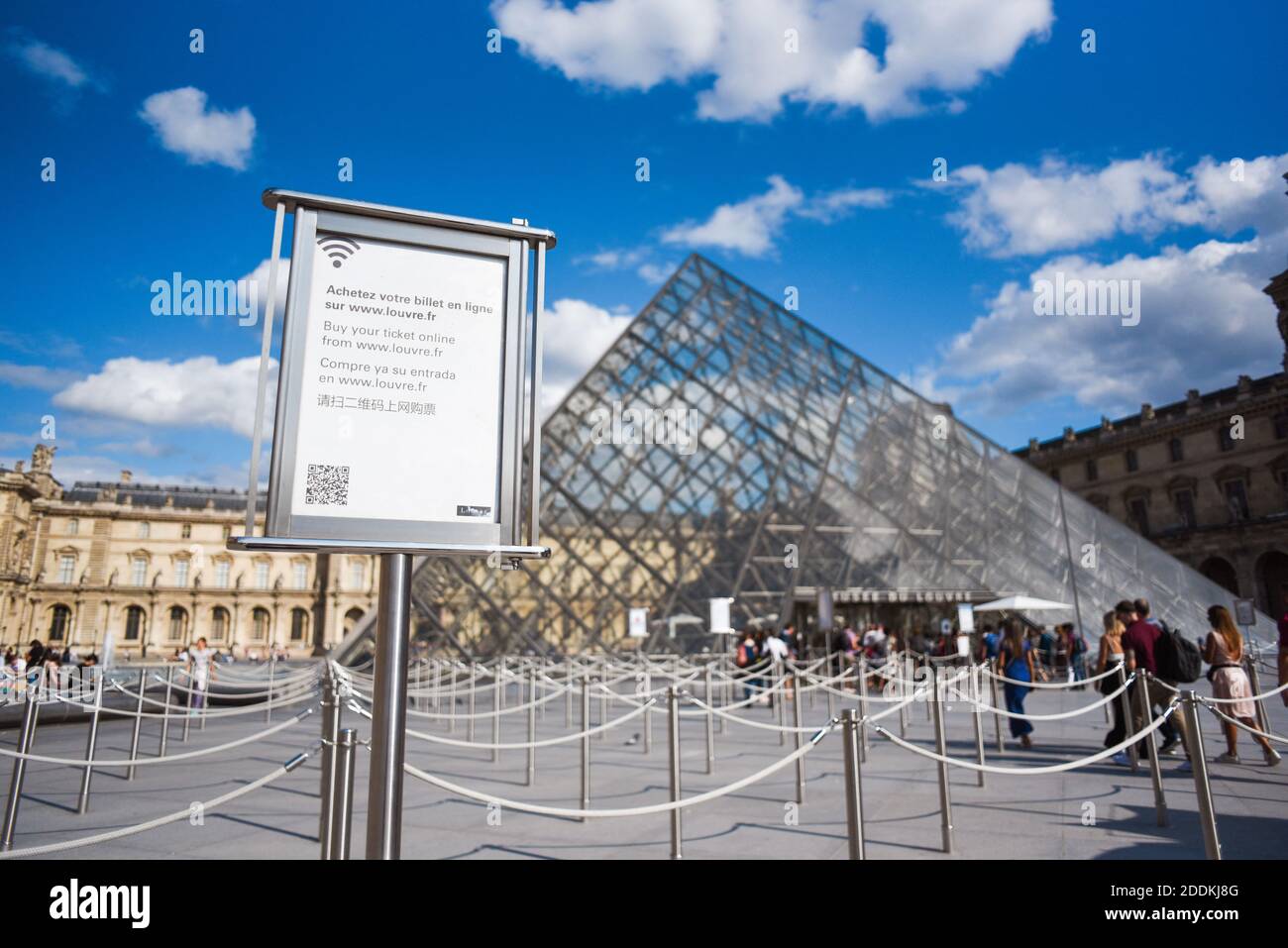 Tourists walk in front of the Louvre on July 31 2019 in Paris 