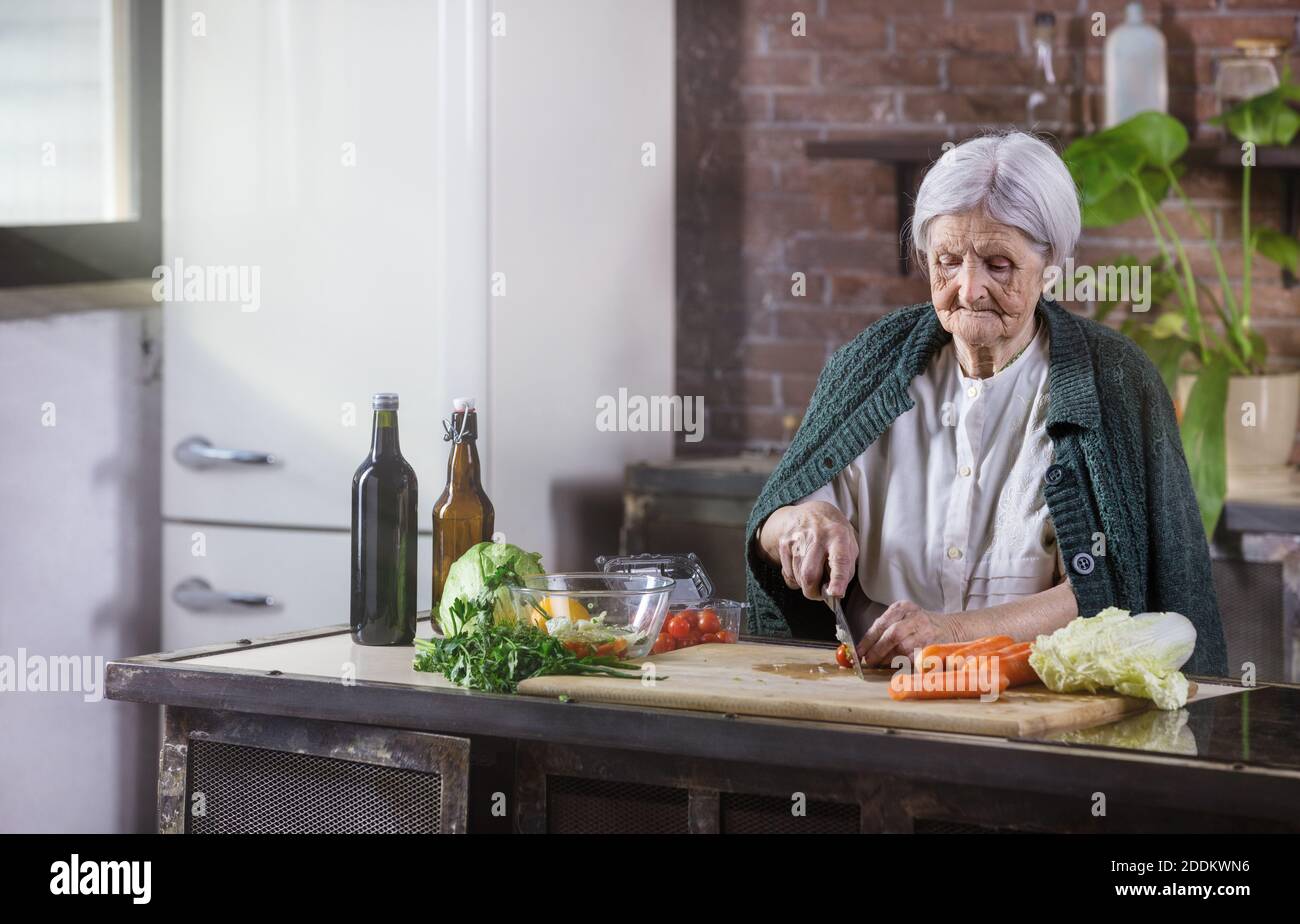 Senior woman chopping fresh vegetables for salad. Healthy eating habits. Stock Photo