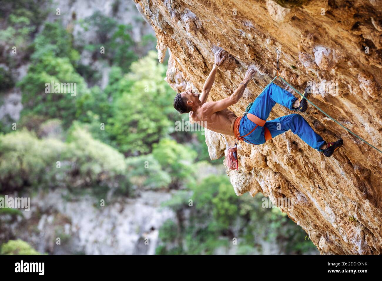 Rock climber on overhanging cliff. Caucasian male climber gripping