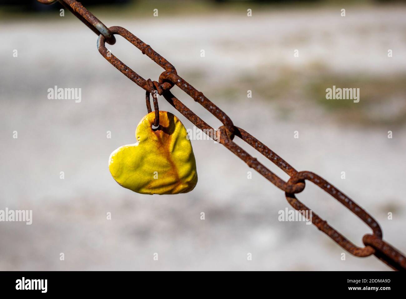 a yellow heart hanging on a rusty chain Stock Photo