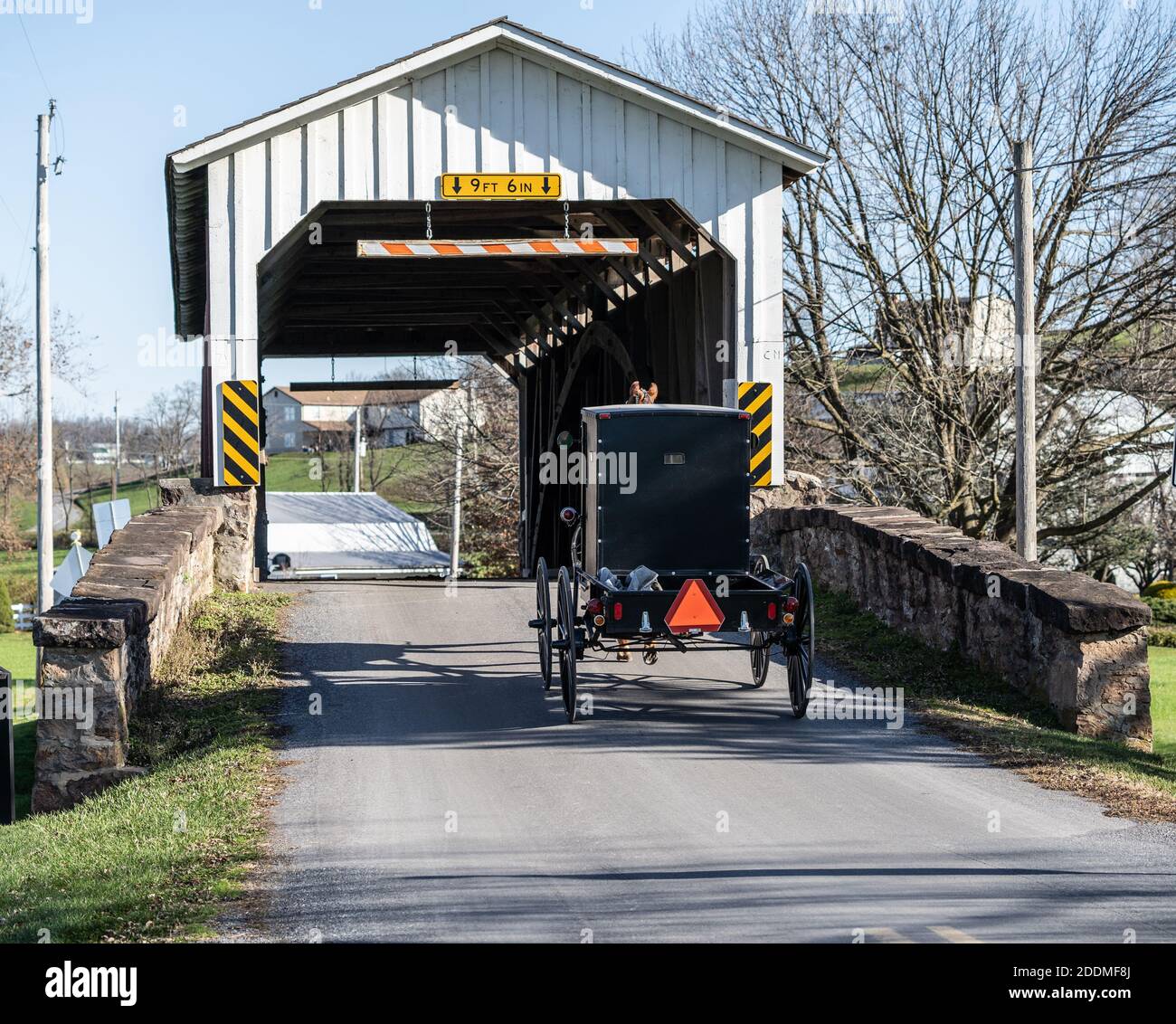Amish buggy crosses covered bridge in rural Lancaster County, Pennsylvanai Stock Photo