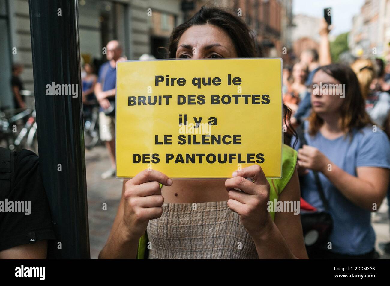 Protester with yellow sign "Worse than the sound of boots, there is the  silence of the slippers" (Pire que le bruit des bottes, il y a le silence des  pantoufles). For the