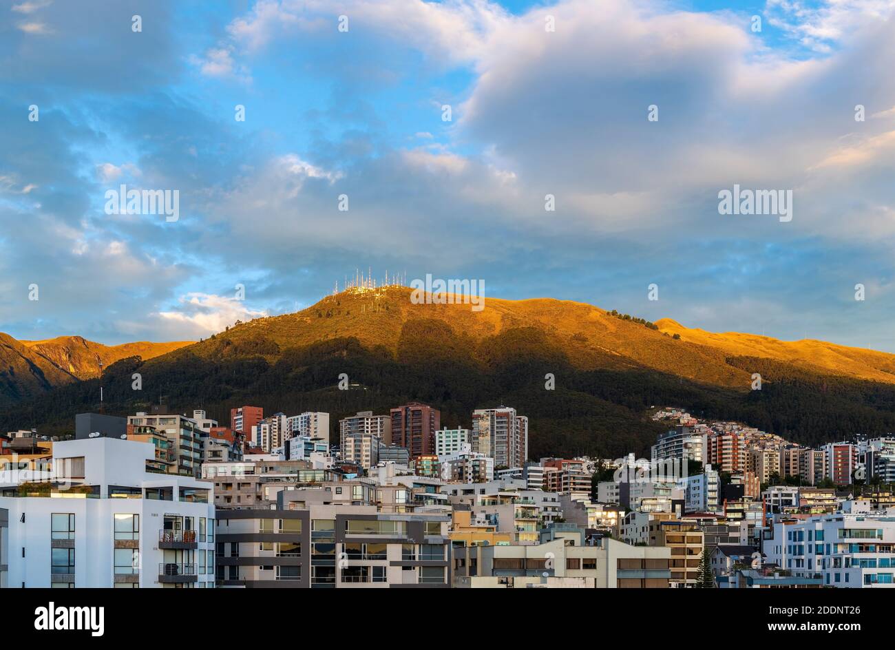 Cityscape and aerial view with skyscrapers of the modern Quito city at sunrise with Pichincha volcano, capital of Ecuador in the Andes mountains. Stock Photo