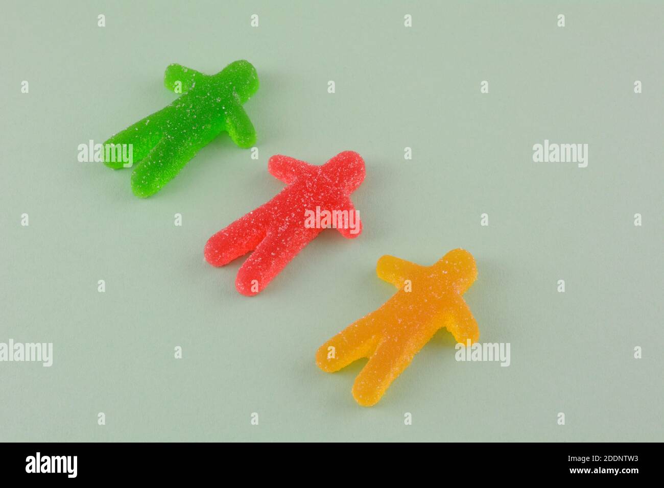 Three fruit chew gummy candy in shape of human on green background