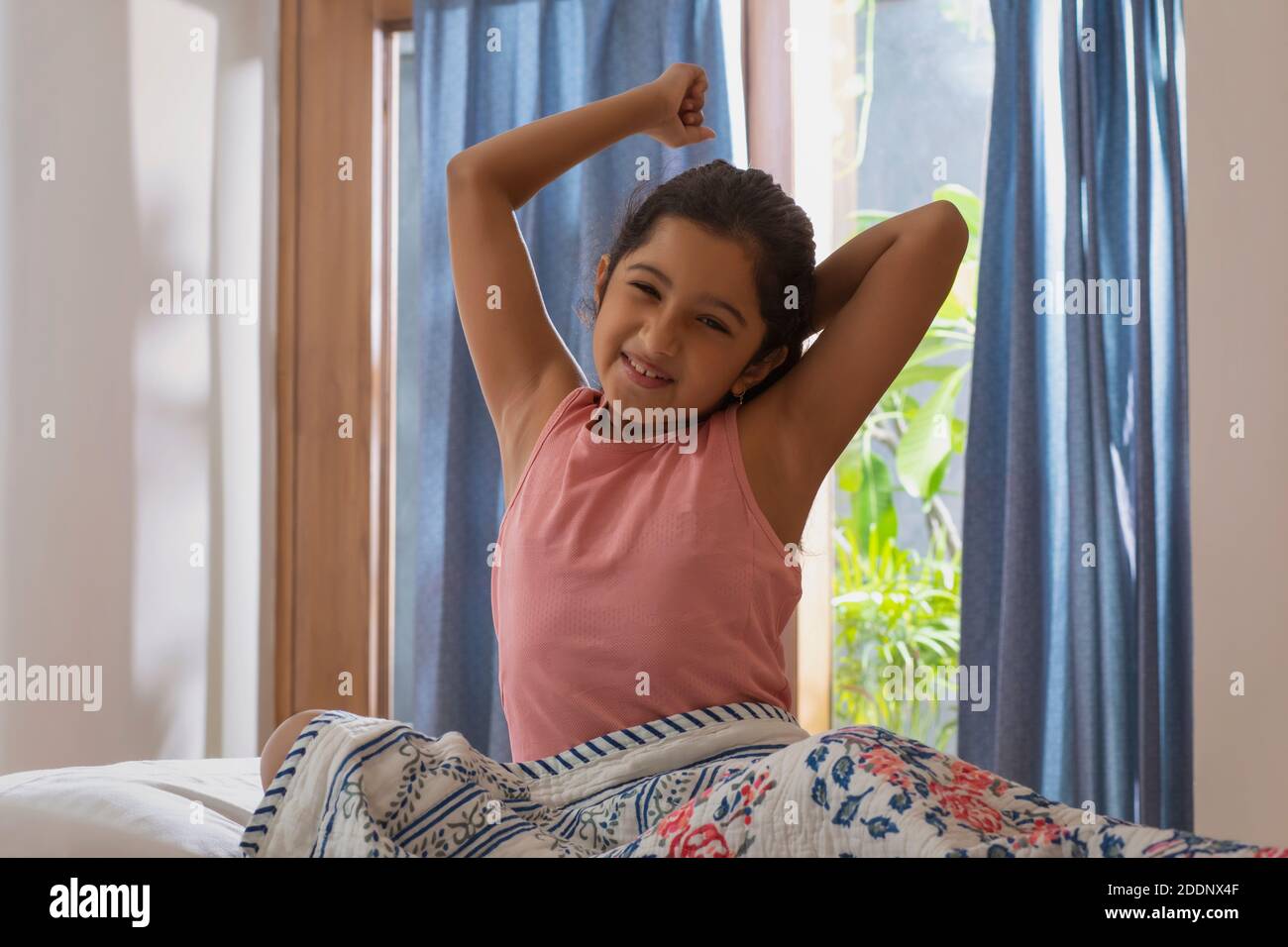 Young girl sitting on bed stretching in the early morning hours of the day Stock Photo