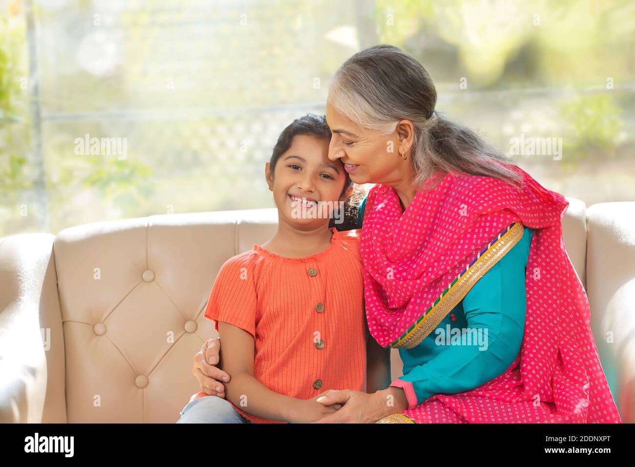 Grand mother holds her grand daughter as the grand daughter looks in to the camera Stock Photo