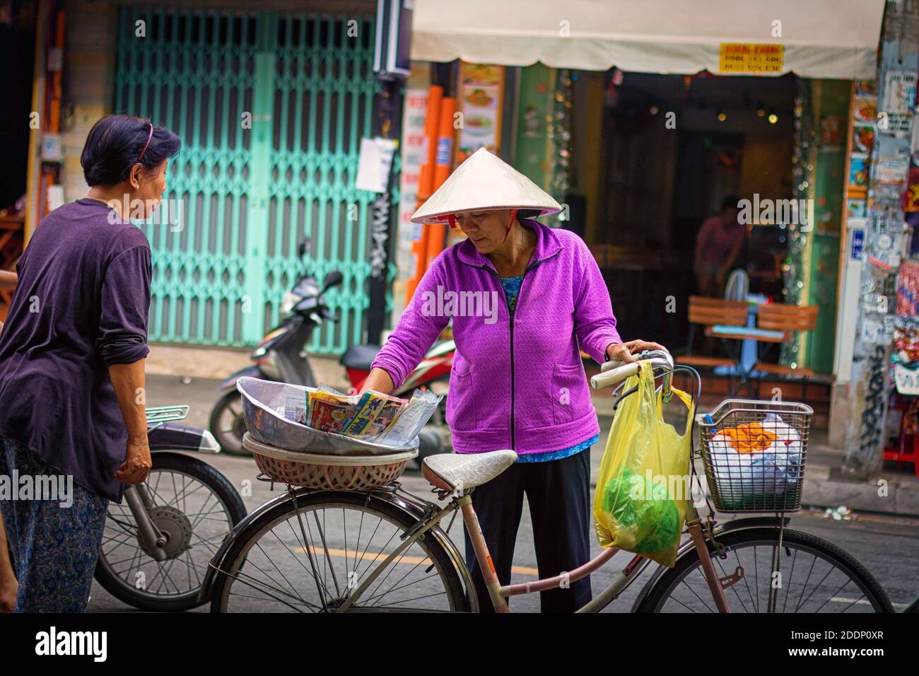 A woman on bike selling food stuffs. Stock Photo