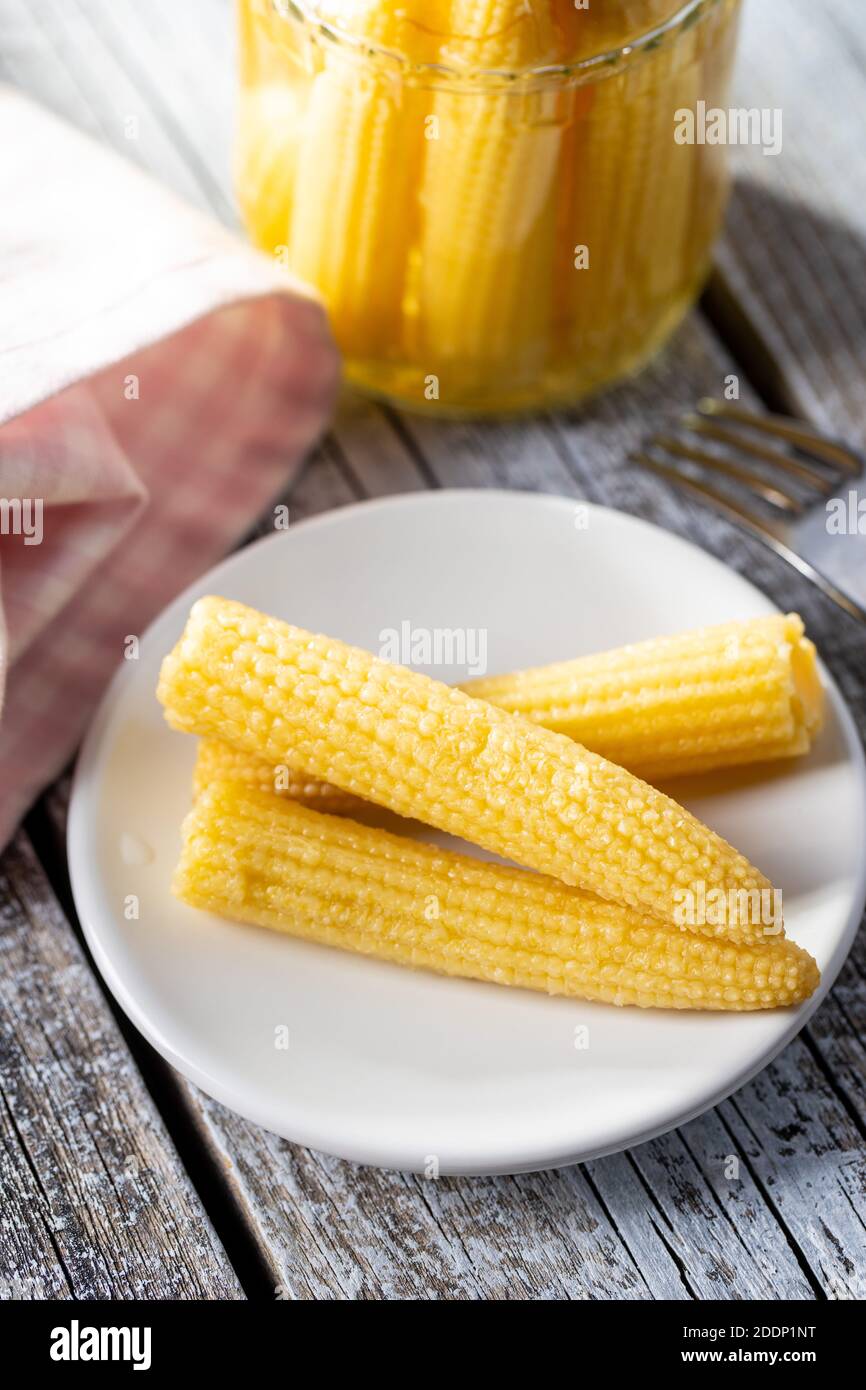 Pickled young baby corn cobs on a plate. Stock Photo