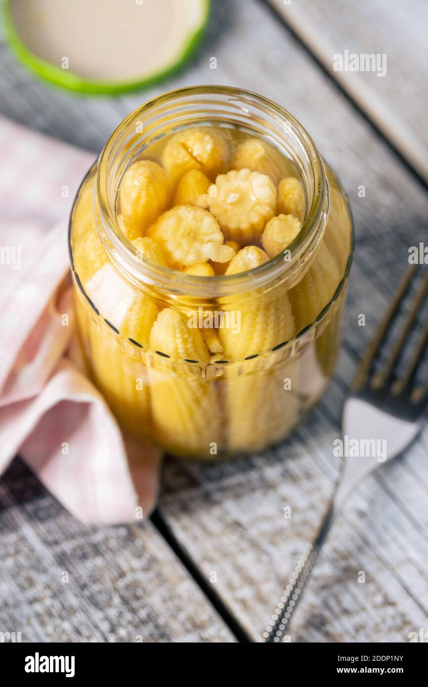Pickled young baby corn cobs in a jar. Stock Photo