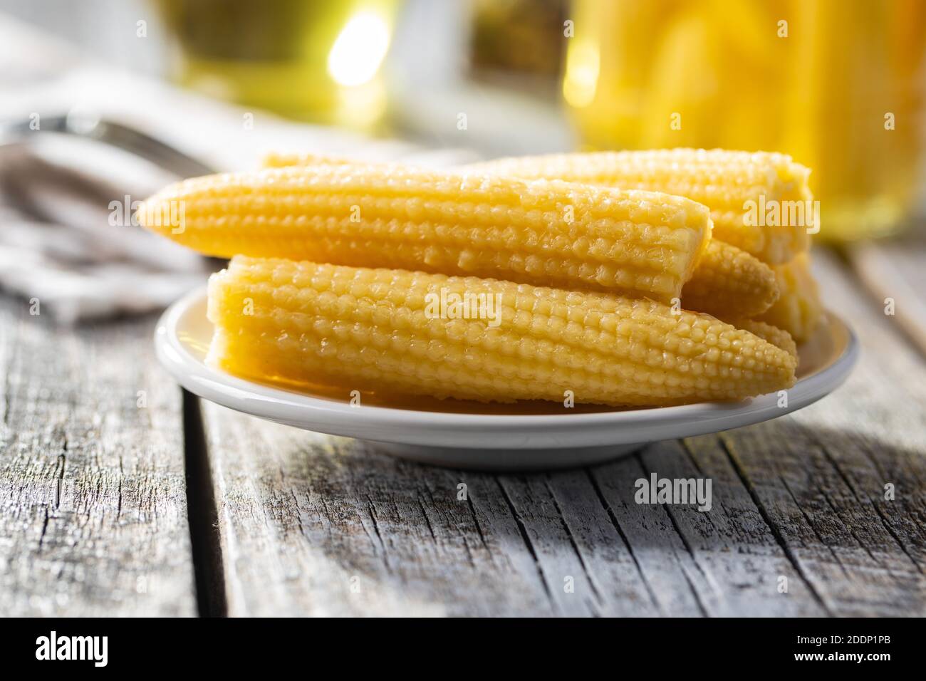 Pickled young baby corn cobs on a plate. Stock Photo