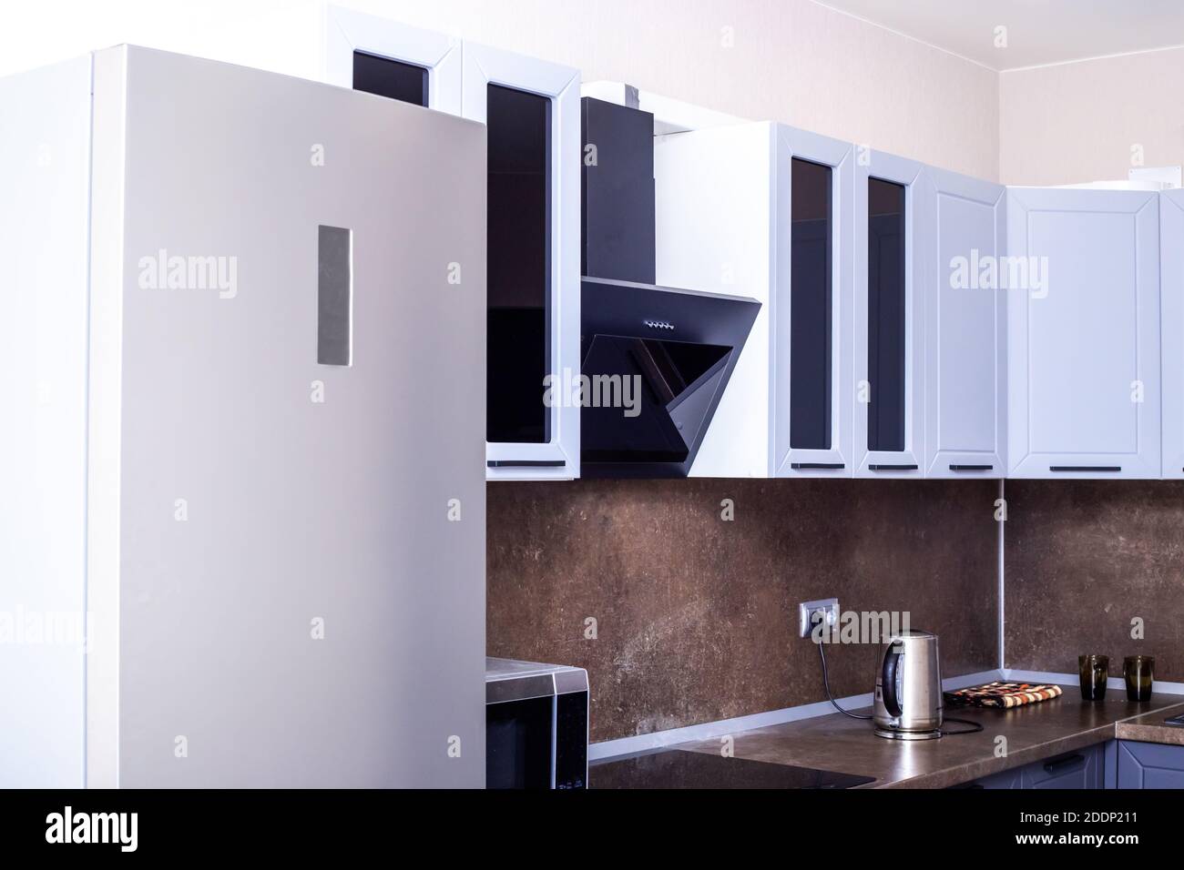 corner kitchen set with dark worktop and large refrigerator Stock Photo