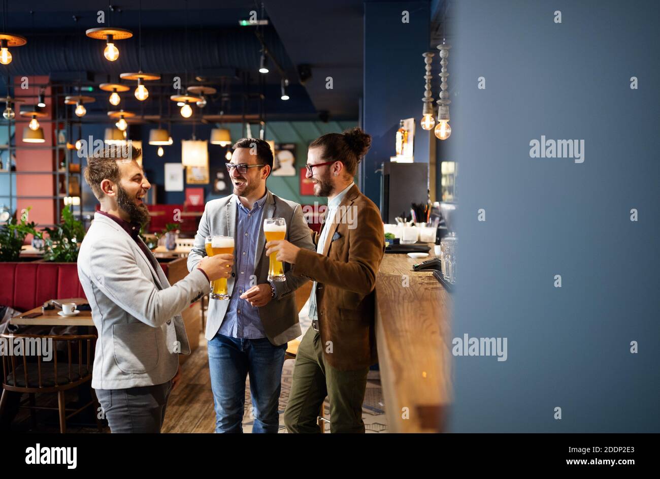 Happy young business men talking and drinking beer in a pub Stock Photo