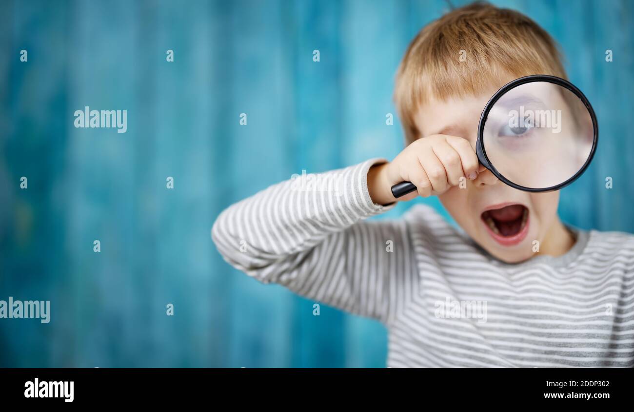 Little boy shocked looking through a magnifying glass Stock Photo