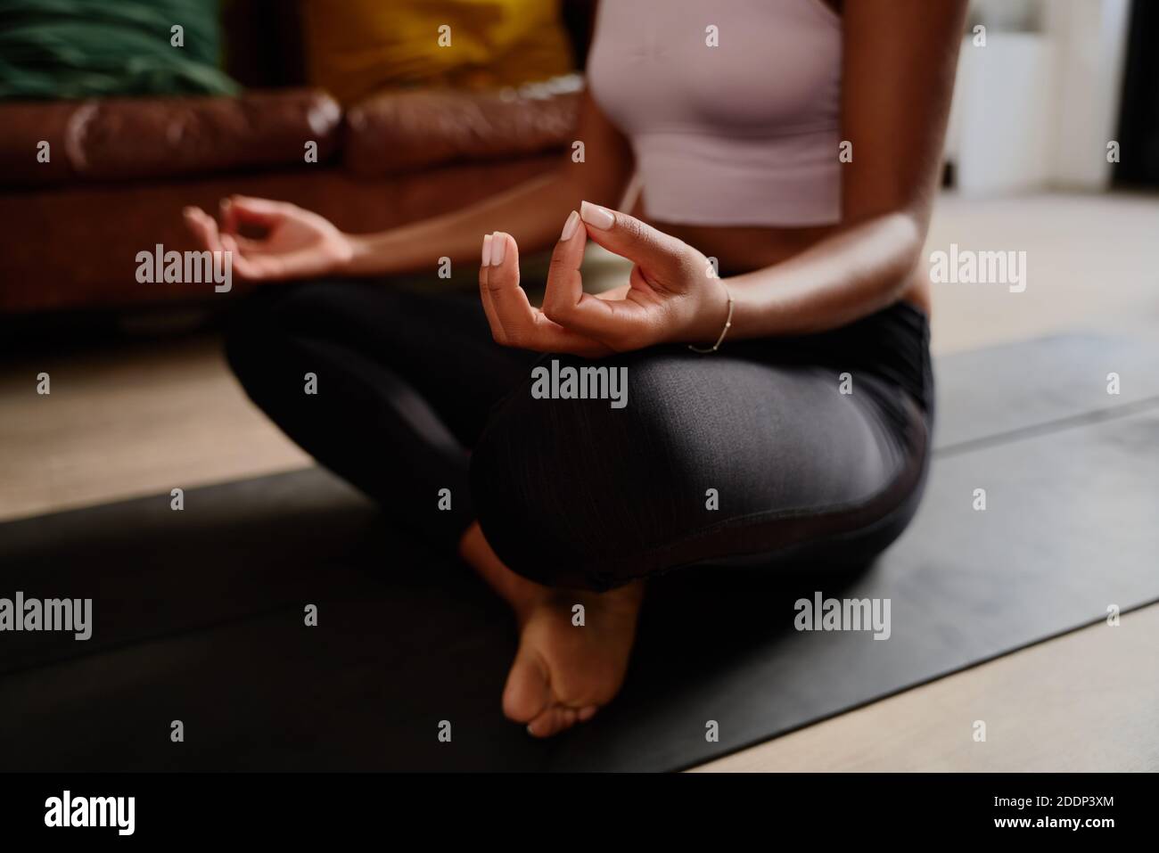 Closeup of hands of young woman sitting in lotus position meditating in the lotus pose at home Stock Photo