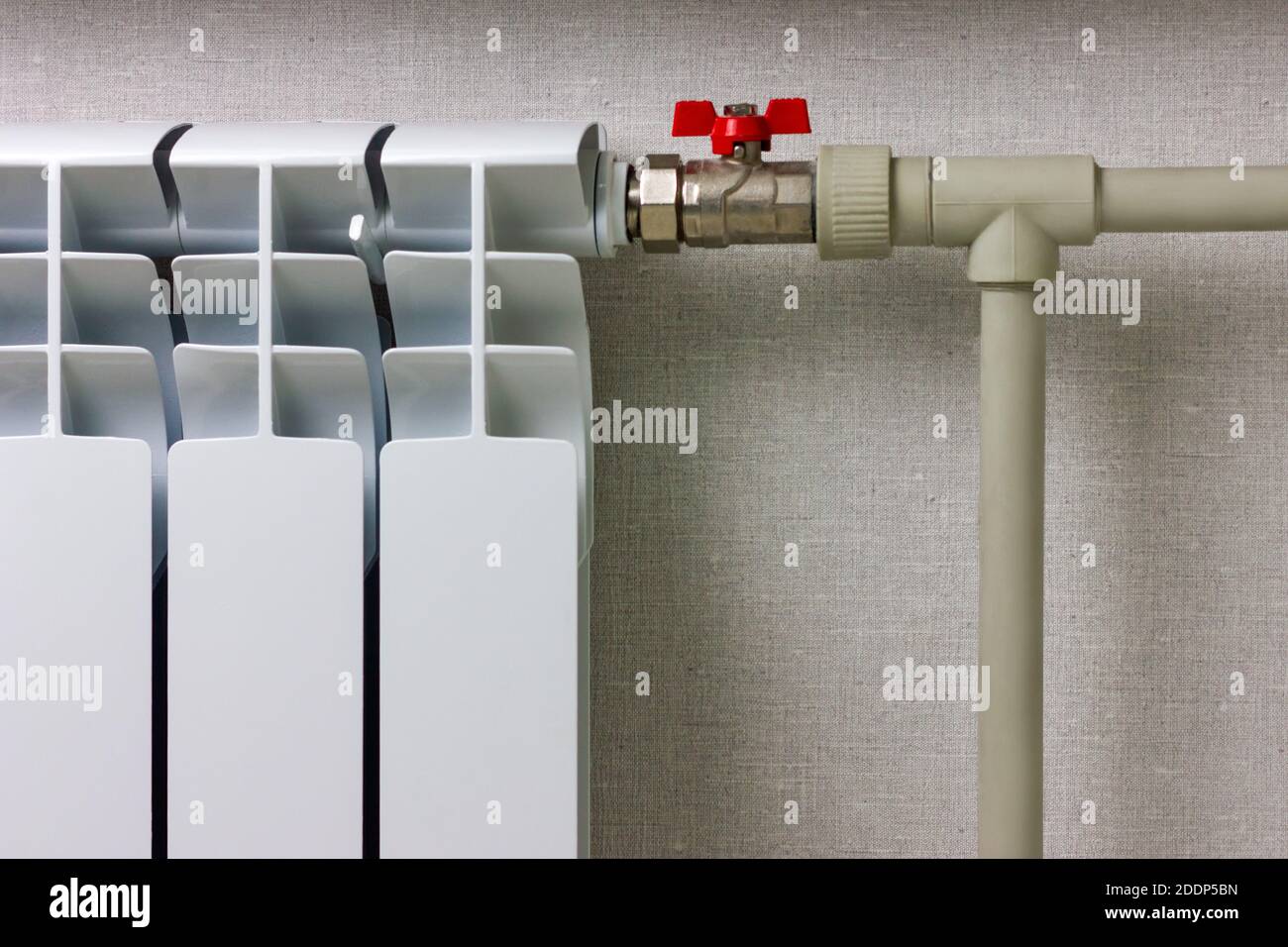 White heating radiator and water pipes with red stopcock Stock Photo