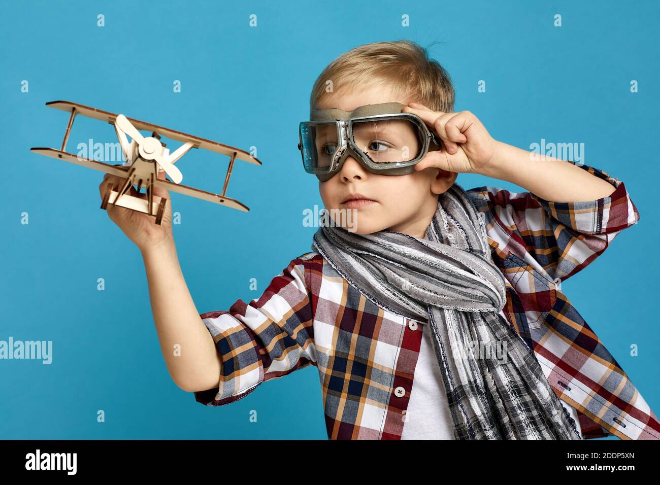 happy child boy in retro glasses and scarf playing with wooden toy ...